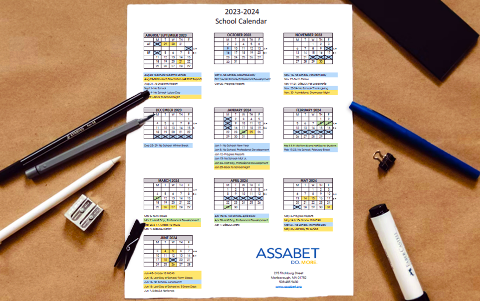 A print out of a one page school year calendar on a table with writing instruments around it on all sides