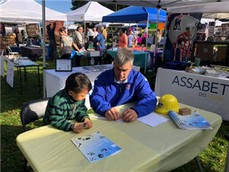 Mr. Hollick with a young child at a table at a community event
