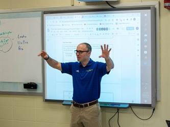 A teacher presenting in front of a smart board