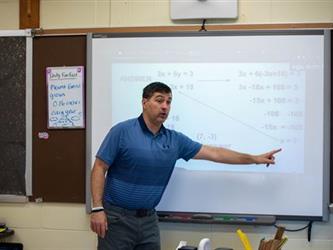 A teacher presenting in front of a smart board