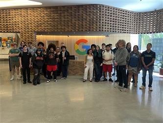 a large group of students in front of the Google logo in a lobby area