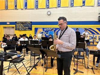 Band teacher and student play in gym