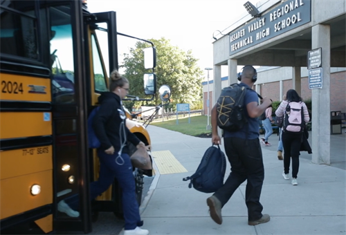 students exit a bus at the school entrance