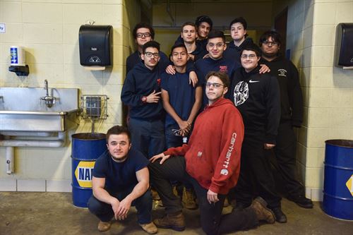 A group of students pose in their shop by a sink